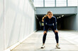 © BGStock72 - Determination shines through as a female athlete catches her breath in a modern urban hallway after an intense workout session