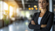 © Thanthara - Professional woman in black suit standing confidently with arms crossed in modern office