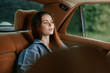 © SHOTPRIME STUDIO - A serene young woman with long brown hair sitting in a vintage car, wearing a denim jacket, reflecting calmness and nostalgia amidst a lush green background.