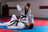 Female taekwondo fighter performing an arm bar on male opponent