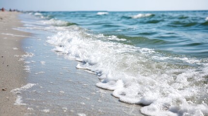 Poster - Soft waves rhythmically wash onto the sunlit sandy shore, creating a serene atmosphere ideal for relaxation and reflection on a clear day