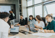 © qunica.com - Multicultural business people collaborate in a modern meeting room. They are actively discussing strategies and brainstorming solutions, showcasing teamwork and corporate communication skills.