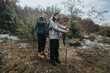 © qunica.com - Three people dressed in winter attire and using trekking poles, preparing for a hike in a serene snow-dusted forest setting, surrounded by trees and fresh air.