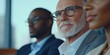 © Denis - The image captures a scene of three men engaged in a formal meeting within an office environment. The central figure is a man with salt and pepper hair, dressed in business attire with a blazer and