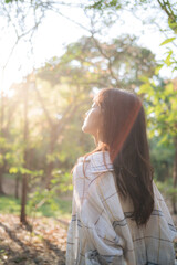Poster - Asian woman enjoying summer sunlight, breathing fresh air in serene forest, surrounded by nature tranquility and warm golden light