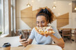 © Dusan Petkovic - Young multiracial woman sitting in fast food restaurant with cellphone and eating pizza.