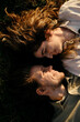 © Ekaterina - Romantic young couple lying face-to-face on the grass, looking into each other's eyes lovingly. Top view portrait.