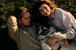 © Ekaterina - Young couple lying on the grass playing and cuddling with their happy Australian Shepherd dog. Aussie blue merle having fun outside with owners.