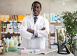 © JackF - Experienced middle-aged African American pharmacist in white coat standing with arms crossed and confident smile behind pharmacy counter, ready to assist customers with medications..