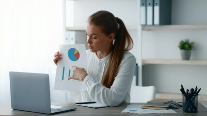 Leinwandbilder - A young woman confidently presents data charts to an unseen audience in a bright, modern office. She is engaged in a discussion about corporate strategies and performance metrics.