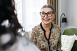 © shurkin_son - Selective focus on happy joyful female psychotherapist in stylish glasses laughing while talking to her client, adding little humor as psychotherapy trick sitting on chair in her cabinet