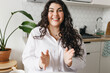 © shurkin_son - Portrait of excited young caucasian plus size woman gesticulating while talking, sitting at kitchen table, sharing funny story having video call or recording podcast for social media