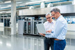 © Westend61 - Two businessmen discussing work on a laptop in a production hall