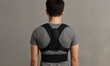 © AiDesign - back view of person wearing wearable posture corrector isolated on grey background Featuring support and alignment of back bone after injury