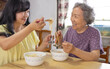 © Tom Wang - Happy elderly mother and daughter eating noodles at home