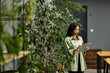 © LIGHTFIELD STUDIOS - Elegant young woman engaged in digital work in a modern office surrounded by greenery