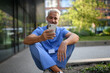 © Halfpoint - Healthcare worker outside hospital and checking phone during break.