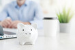 © Kowit - A piggy bank sits on a desk, symbolizing saving and financial planning in a modern workspace.