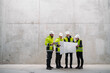 © Halfpoint - Team of engineers and construction workers reviewing blueprints, building site.