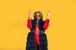 © PintoArt - Senior woman showing middle fingers on yellow background