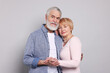 © New Africa - Portrait of lovely senior couple holding hands on grey background