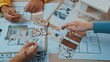 © InfiniteFlow - Hands actively participate in a dynamic interior design session, exploring vibrant materials and detailed floor plans, emphasizing teamwork and creativity in design. SACTR