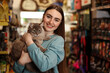 © New Africa - Happy woman with her cute cat in pet shop. Space for text