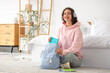 © Pixel-Shot - Female Indian student with headphones taking copybook from backpack in bedroom