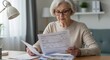 © Vyatcheslav - Elderly woman reviewing paperwork at home office