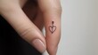 © Atthapon - A hand holding a small heart tattoo with an arrow pointing to it