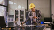 © NanSan - Two Asian businessmen wearing engineer hats table, discussing solar panels and wind turbines. They plan environmental projects, focusing on solar energy solutions and renewable energy installations