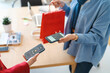 © Studio Marmellata - A shopper is using their phone to make a contactless payment after a purchase. It's a convenient way to pay, especially when you're on the go.