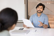 © fizkes - Indian HR manager interviewing female applicant in office. Financial advisor consulting bank client about mortgage or loan terms, holds legal paper document provide information, sell company services