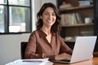 © video - woman working on laptop at desk in modern office with natural light and bookshelves, focused and professional mood