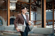 © bongkarn - Brown suit man with glasses walking while holding a coffee cup with laptop and notebook in the cafe.
