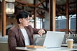 © bongkarn - Brown suit asian man with glasses is looking at his wristwatch while sitting in cafe or coffee shop.