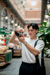 © bongkarn - Asian man wearing glasses in white tee taking photos on his camera in shopping mall or indoor market