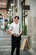 © bongkarn - Asian man wearing glasses in white tee looking around with camera in hand at shopping mall or market