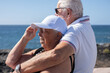 © luciano - Caucasian senior pensioner couple embrace sitting face the sea enjoying freedom and vacation, two elderly people in retirement stay together in good harmony. Horizon over water