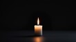 © DigitalDruid - Illuminated small white candle with a flame burning on a dark table surface with copy space in the background