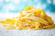 © Victor - Pile of raw tagliatelle pasta rests on a floured surface, highlighting its golden texture and freshness representing  traditional italian cooking, and homemade food.