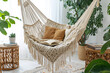 © utaem2022 - Comfortable macrame hammock swinging in cozy living room with open book