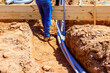 © ungvar - Construction worker positions wooden beams above foundation trench while laying out electrical pvc pipes