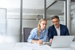 © Stock 4 You - Mature focused senior mentor leader man showing young woman manager project on laptop in modern office. Two partners, team of professional business people working, studying, writing notes sit at desk