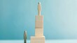 © yong - Wooden human-shaped figures on stacked blocks with blue background symbolizing inequality.