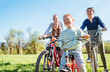 © Soloviova Liudmyla - Smiling father and mother with their two daughters during summer bicycle ride outdoors. They enjoy quality time together in a sunny city park. Happy parenthood, childhood, and active lifestyle concept