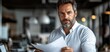 © Muamanah - Confident Mature Businessman Reviewing Documents in Modern Office