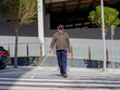 © MalaikaCasal - A blind man crossing the street with his white cane, moving forward cautiously.