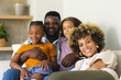 © Wavebreak Media - Laughing Diverse family sitting on sofa in living room, with potted plant, decorative vase