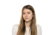 © vladimirfloyd - Close-up headshot portrait of young woman with long straight light brown hair wearing white top, neutral expression, against white background, front view